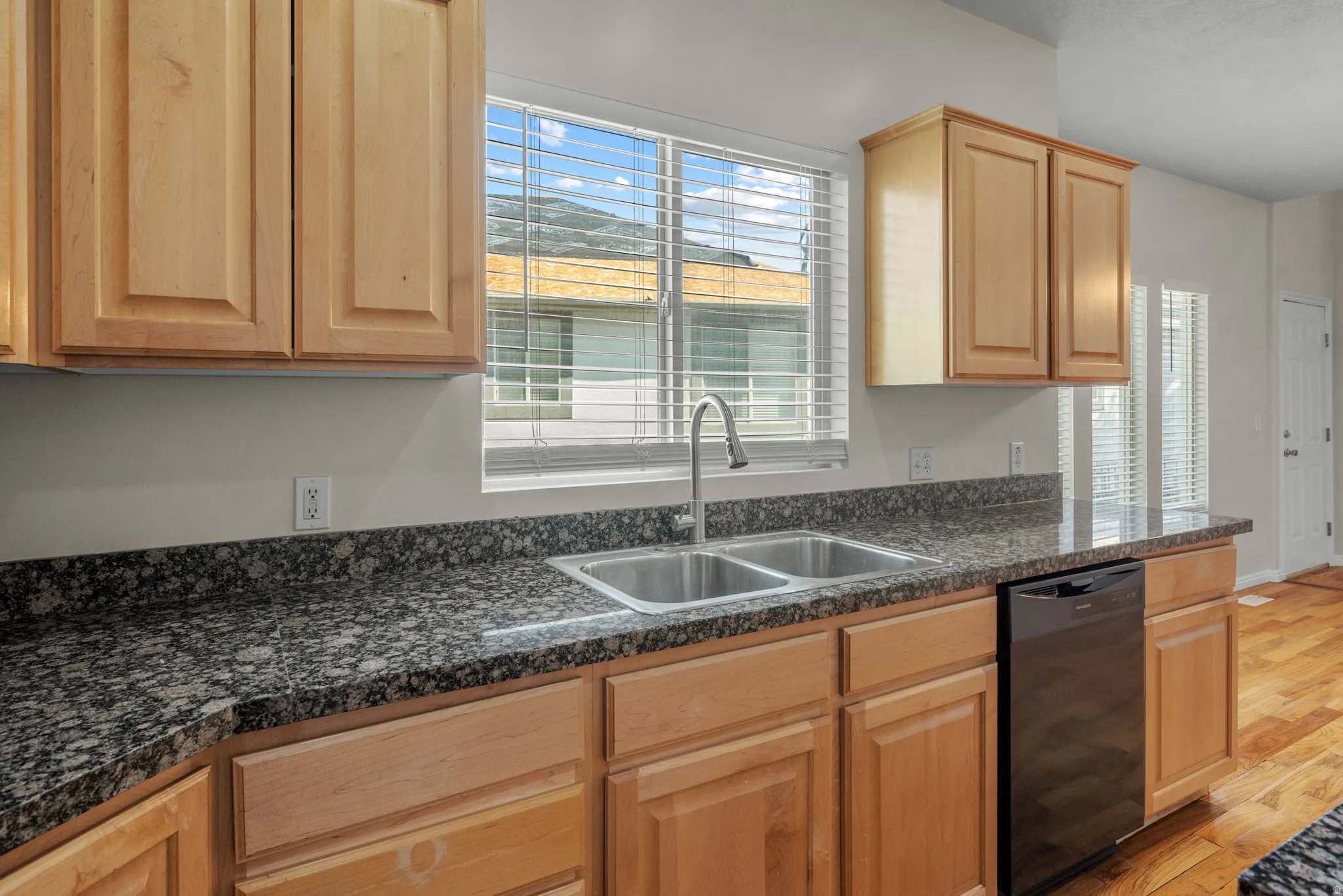 Kitchen featuring dishwasher, light wood-style floors, healthy amount of natural light, and light wood finish cabinets