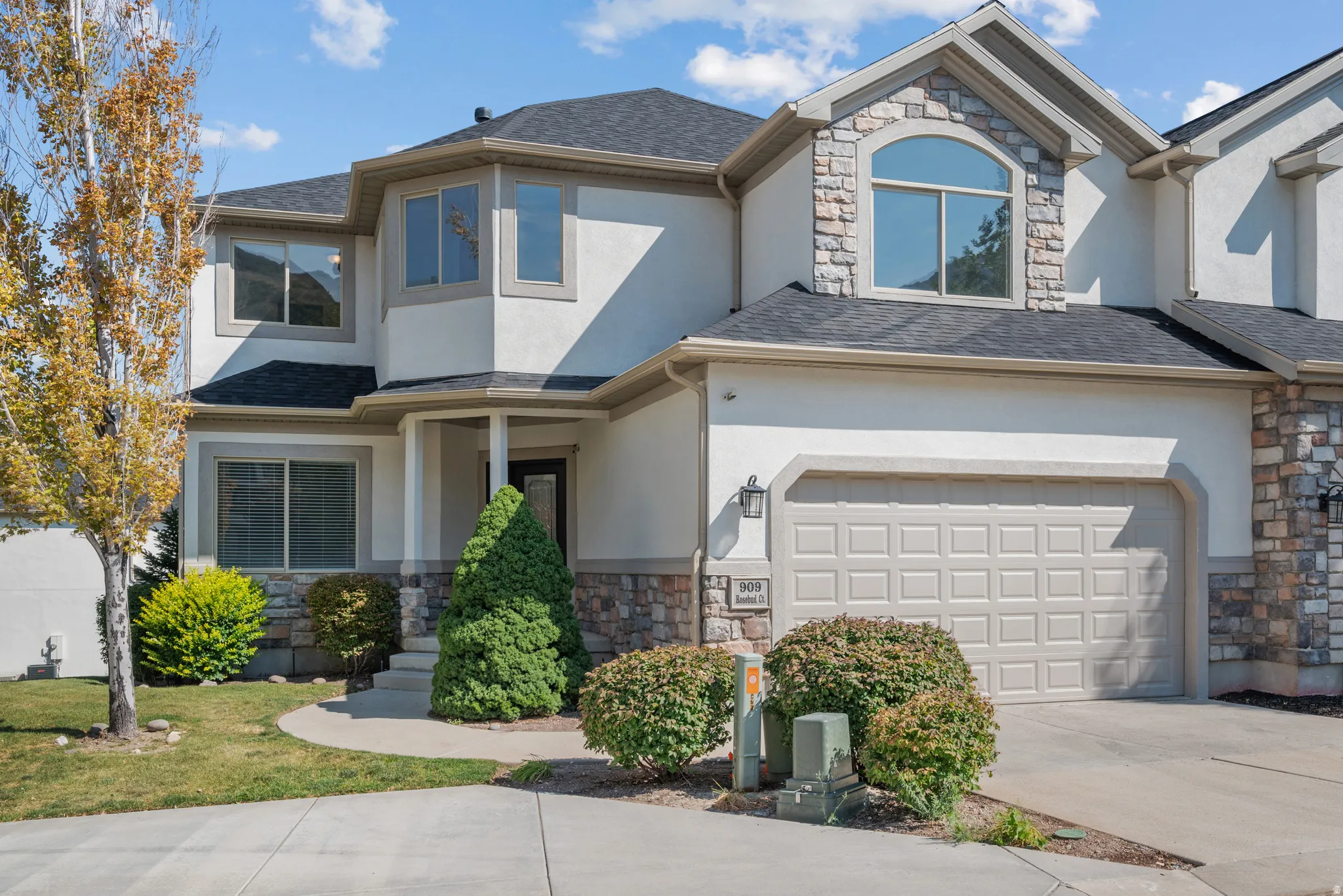 View of front of property featuring stone siding, concrete driveway, stucco siding, and an attached garage