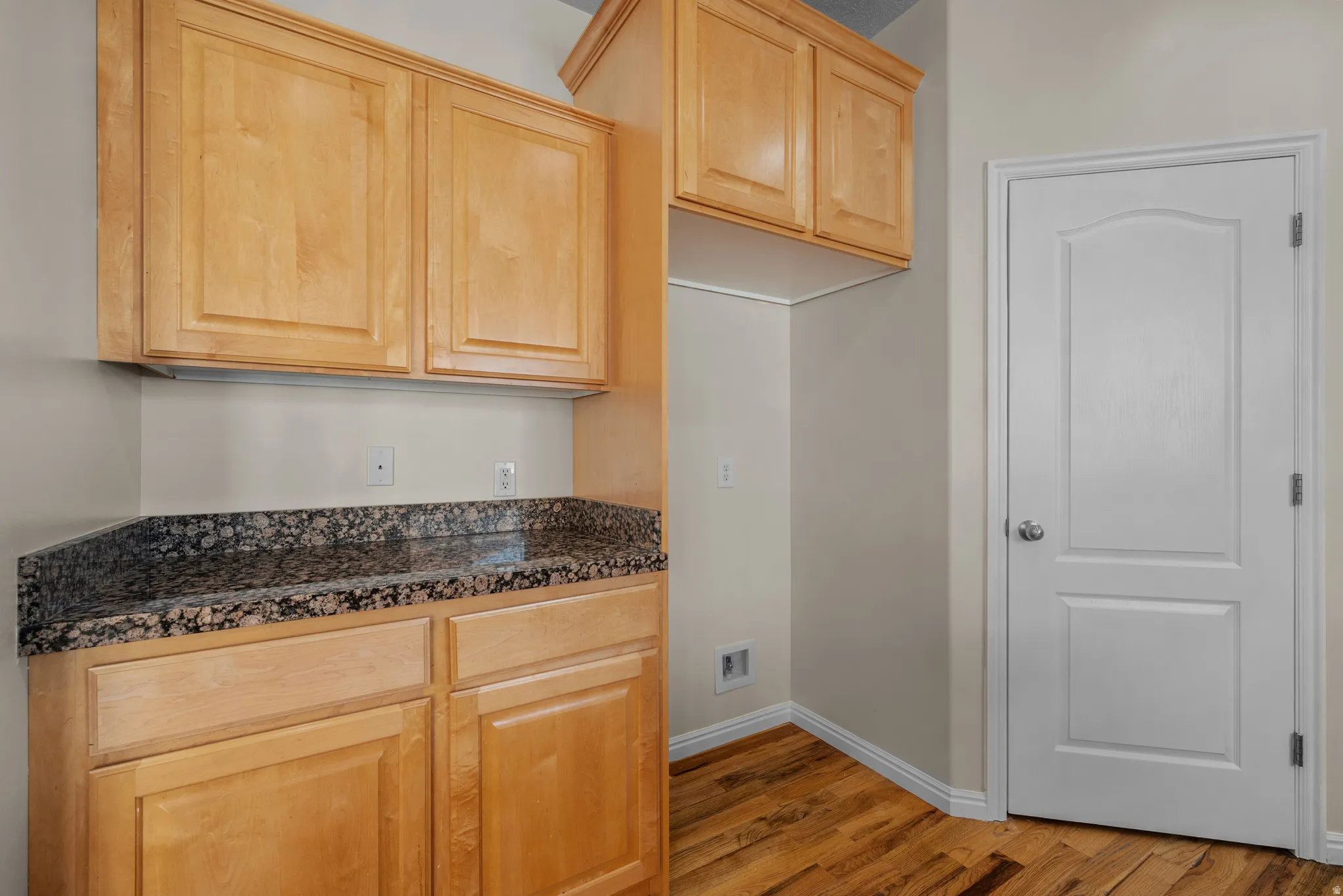 Kitchen featuring light wood finish cabinets, dark stone countertops, and light wood-type flooring