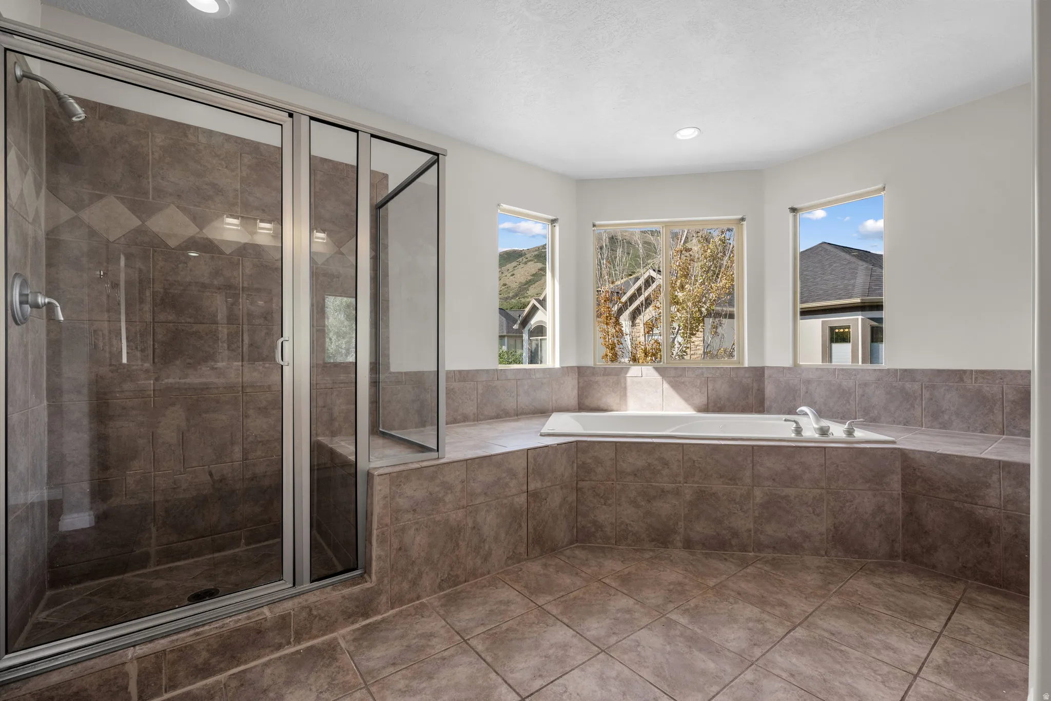 Bathroom with a shower stall, a garden tub, recessed lighting, and tile patterned floors