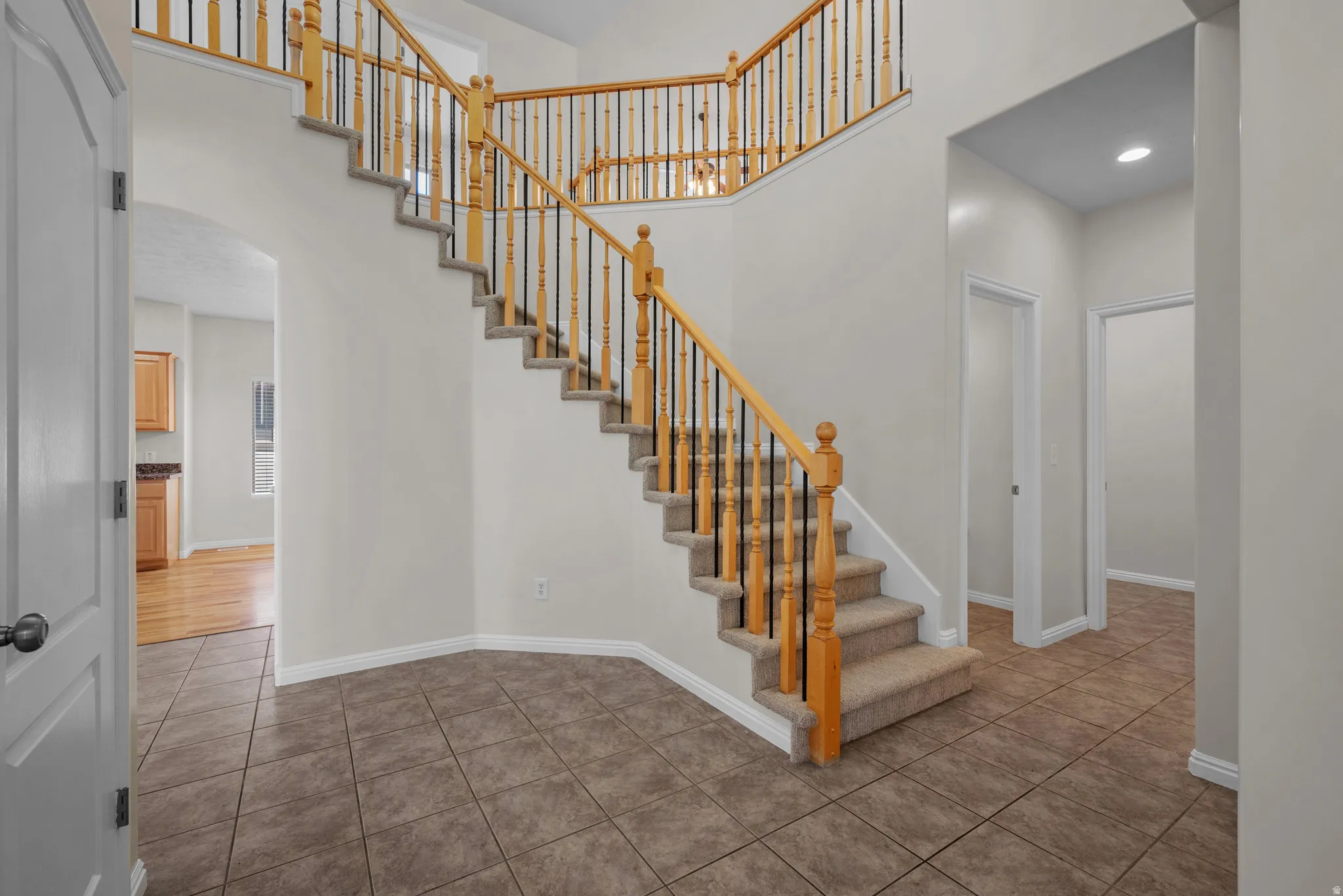 Staircase featuring arched walkways, tile patterned floors, and a high ceiling