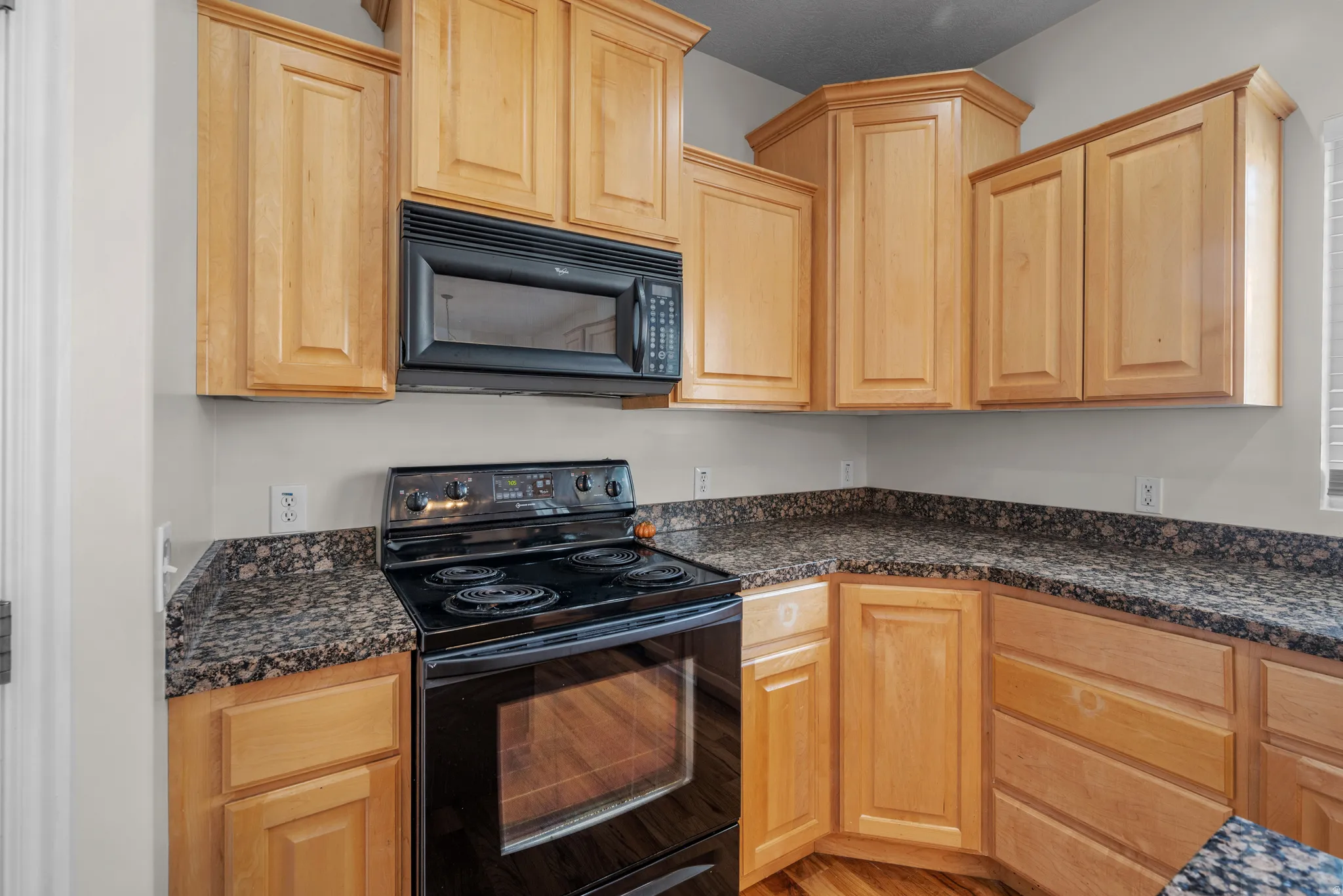 Kitchen featuring black appliances and light wood finish cabinets