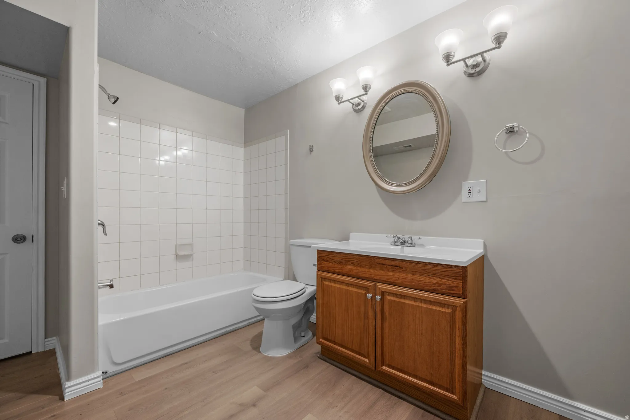 Full bath featuring vanity, shower / washtub combination, light wood-style flooring, and a textured ceiling