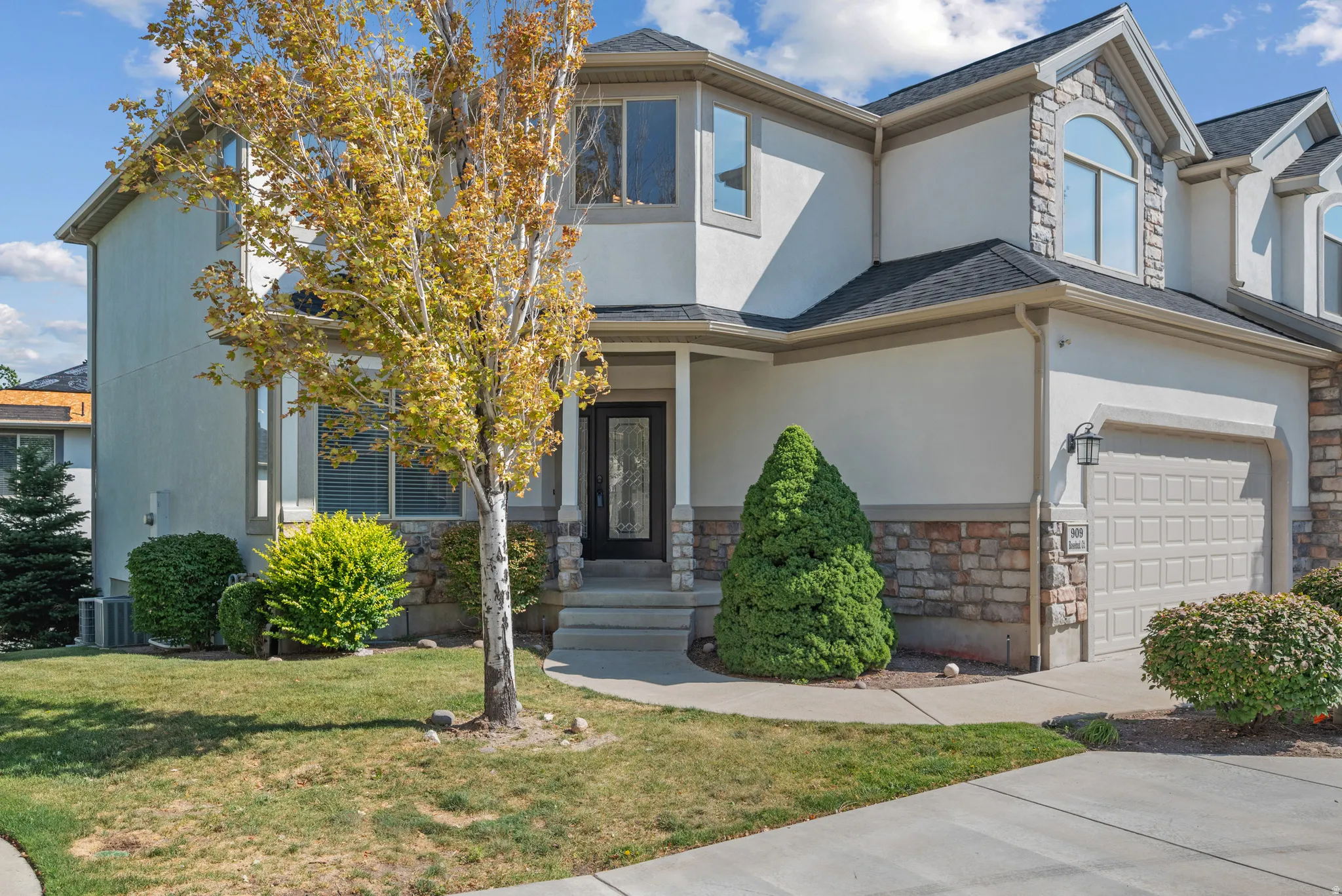 View of front of house featuring stone siding, stucco siding, a front yard, and concrete driveway