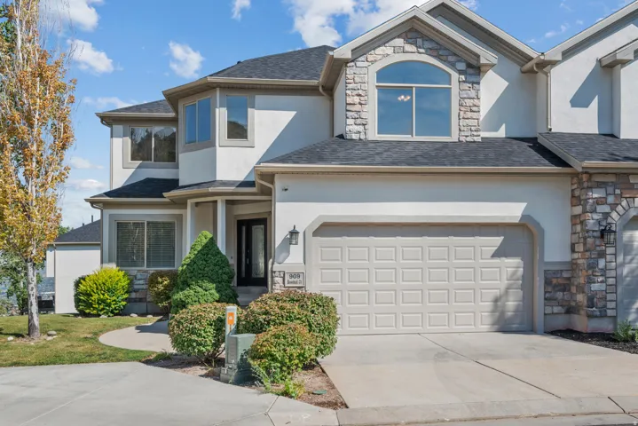 View of front facade with stone siding, concrete driveway, stucco siding, roof with shingles, and a garage