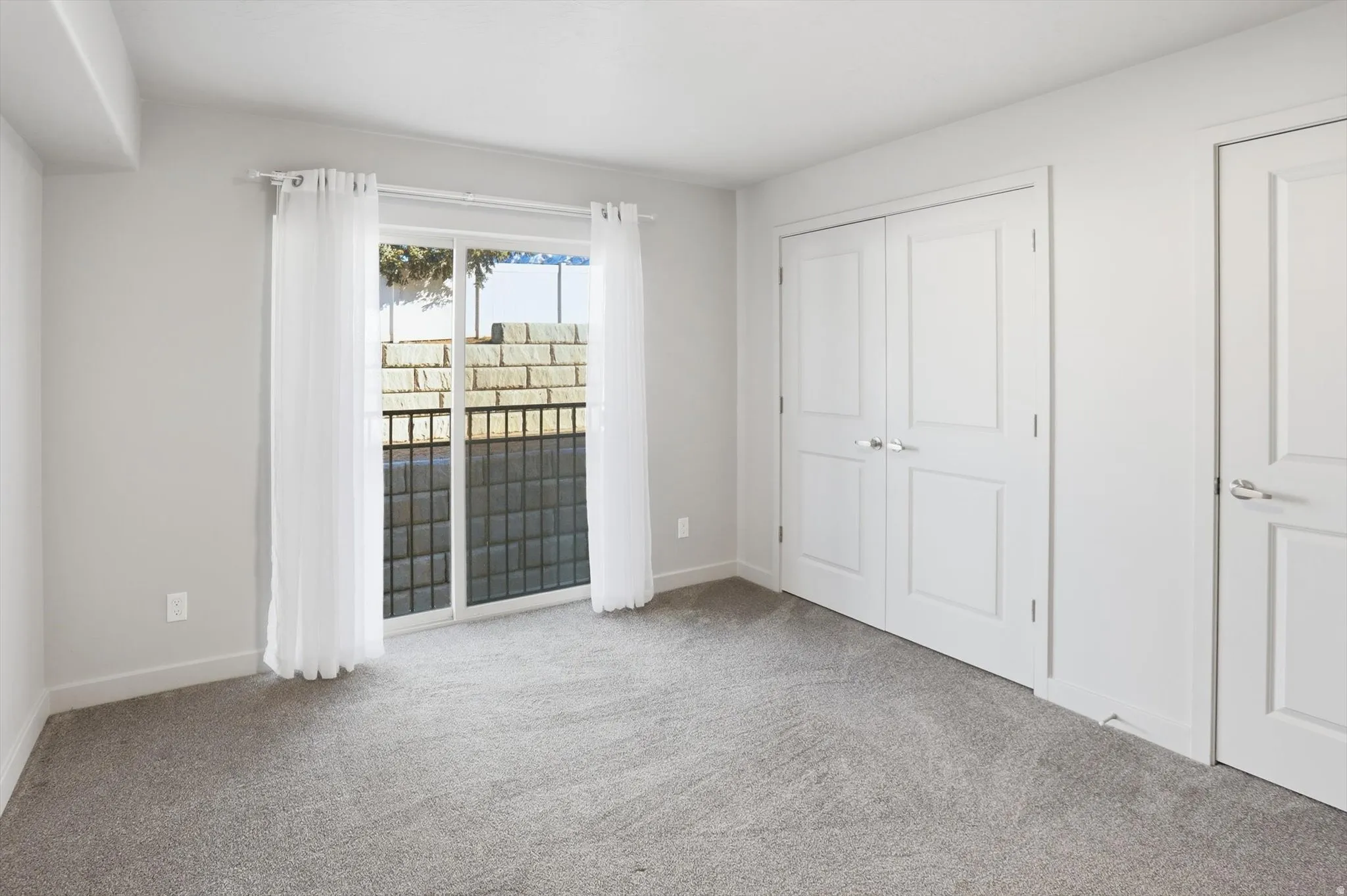 Unfurnished bedroom featuring light carpet, access to exterior, and a closet
