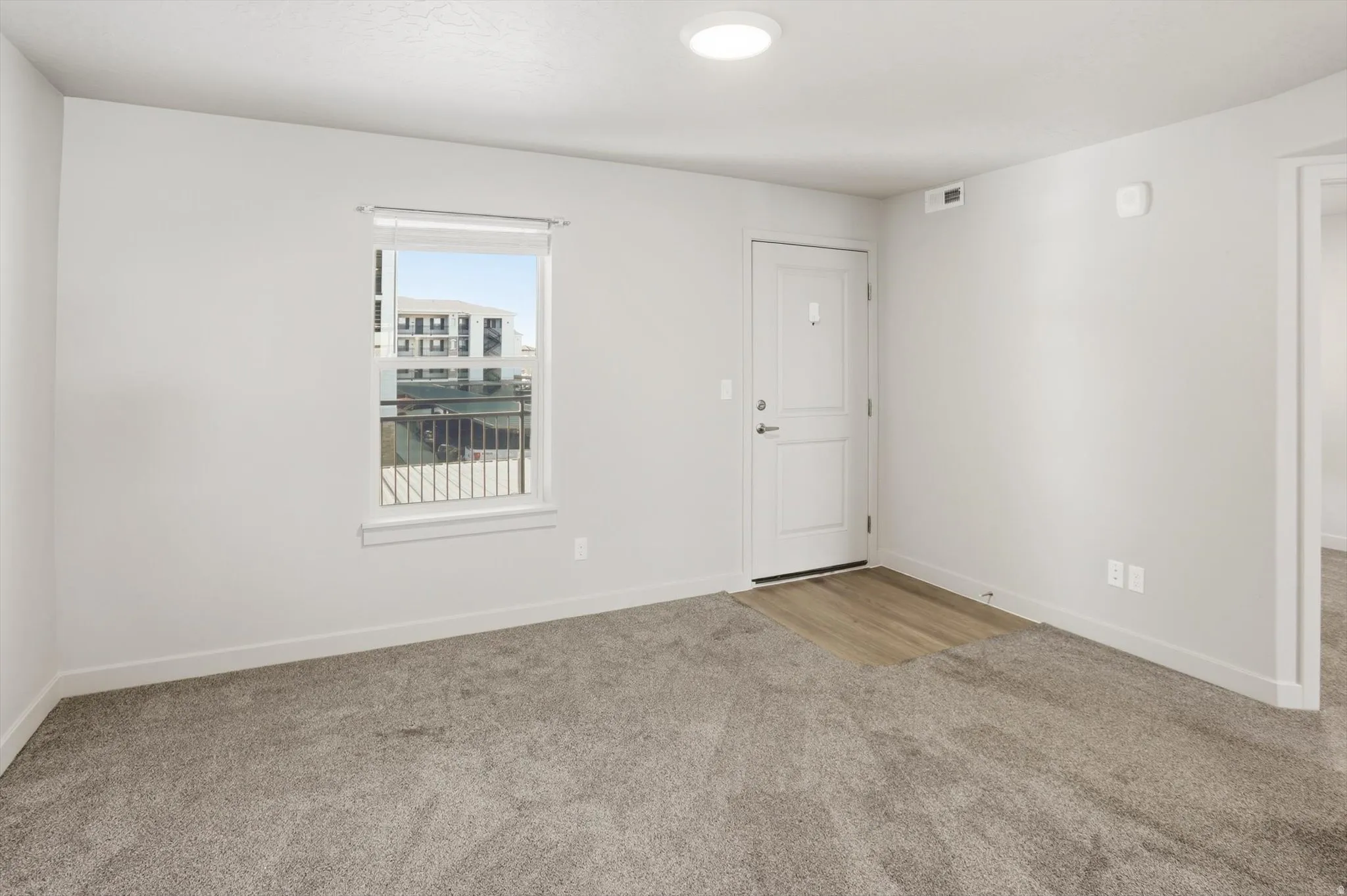 Spare room featuring light carpet and baseboards