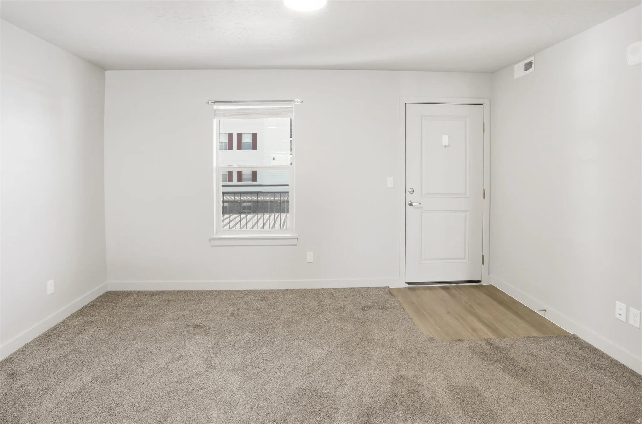 Empty room with light carpet and baseboards