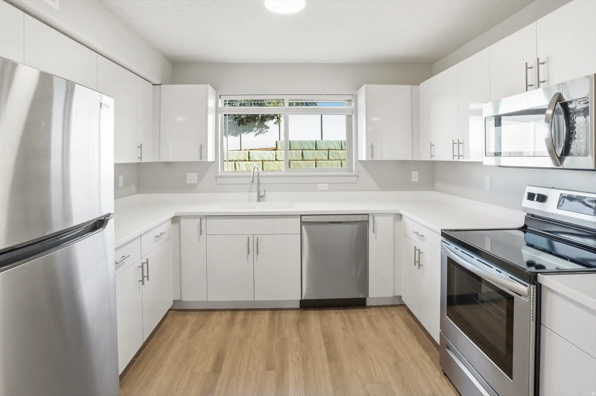 Kitchen with stainless steel appliances, light countertops, and white cabinetry