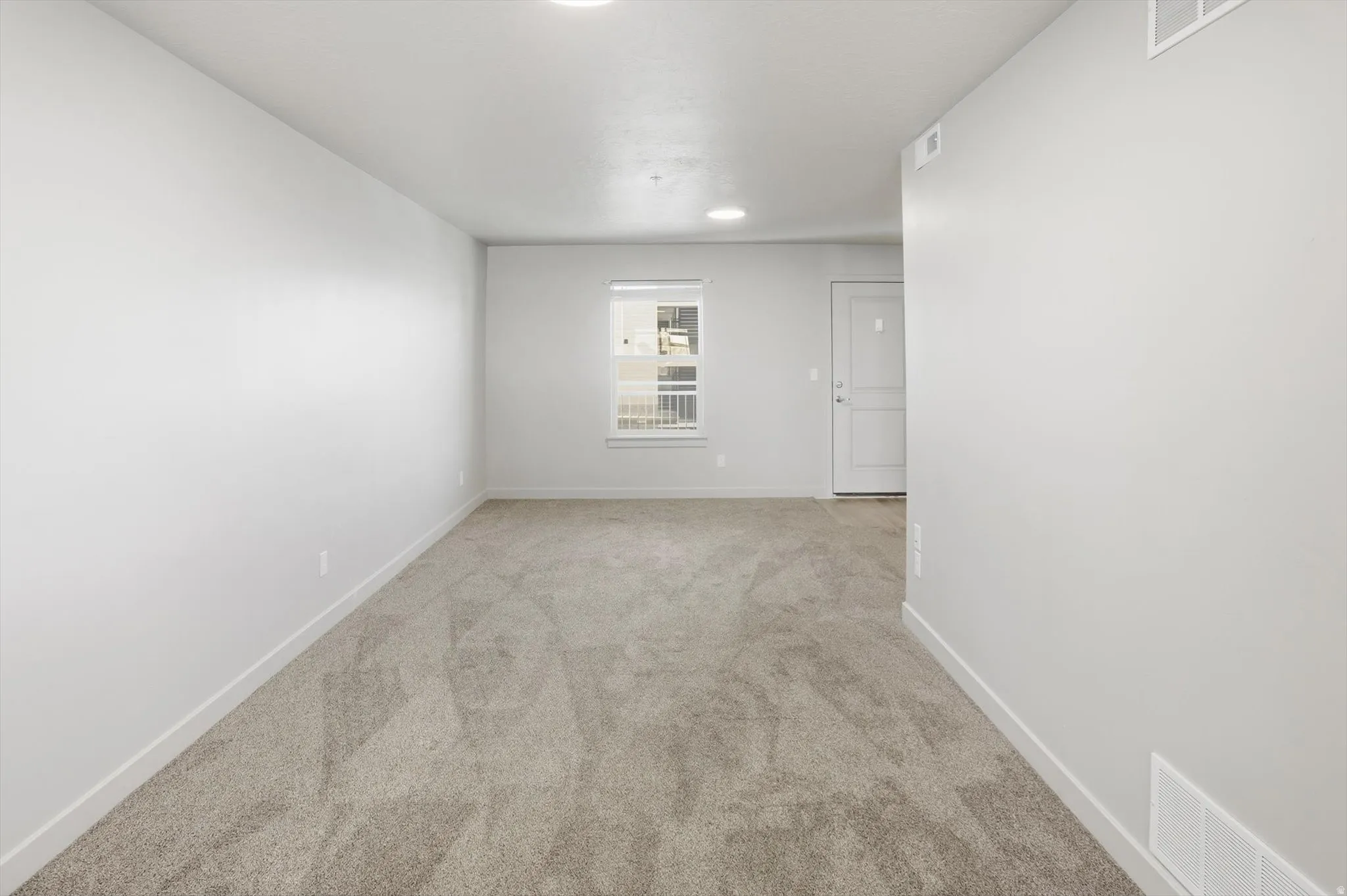 Spare room with baseboards and light carpet