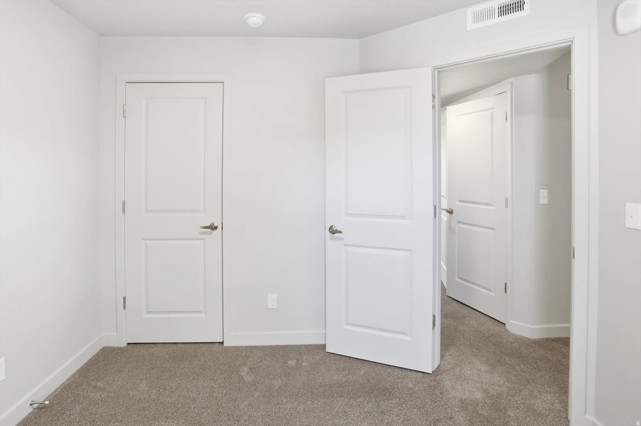 Unfurnished bedroom featuring light carpet and baseboards