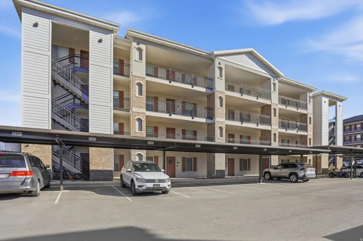 View of apartment building / complex featuring covered parking