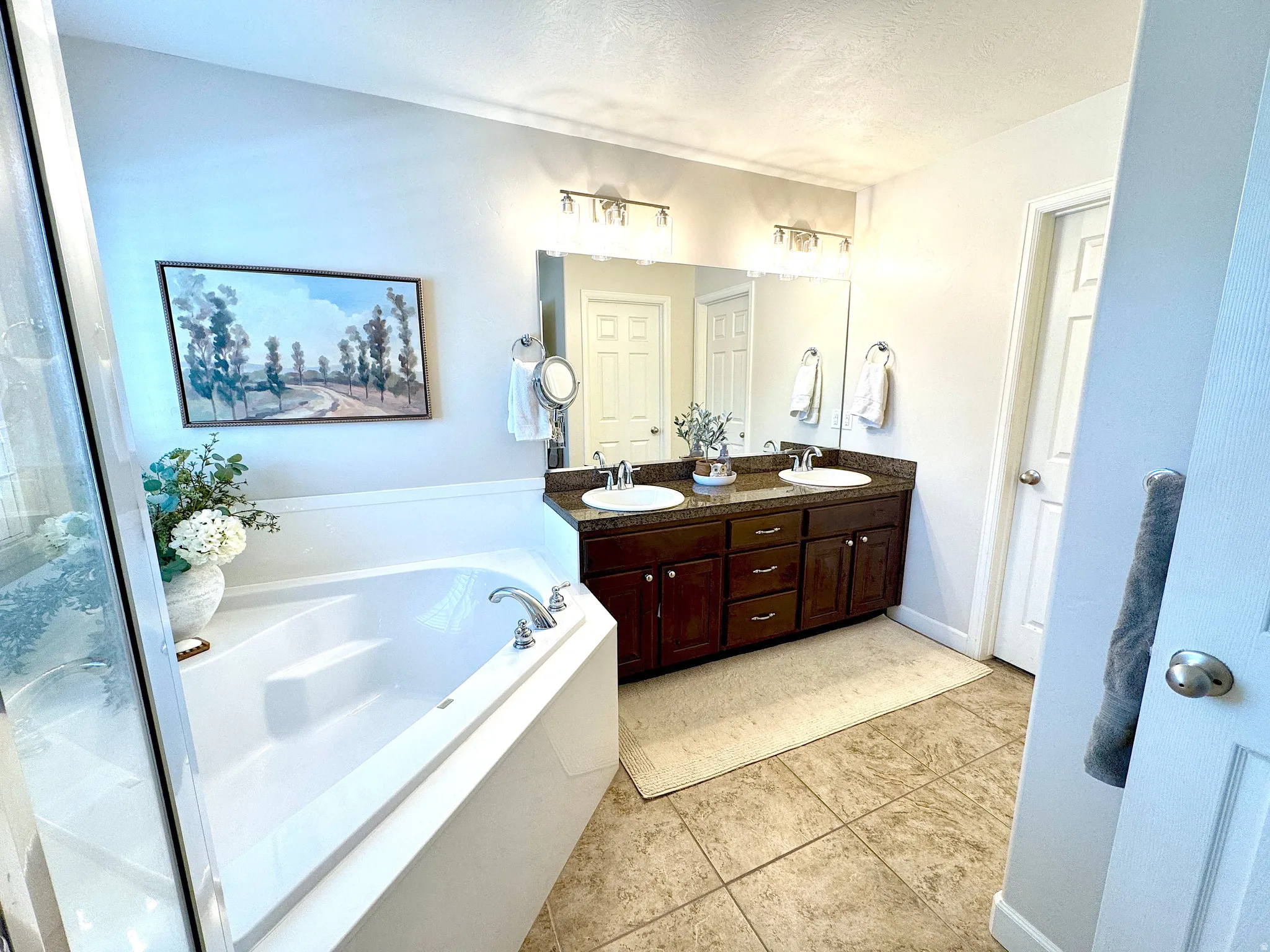 Bathroom with double vanity, a bath, light tile patterned floors, and a textured ceiling