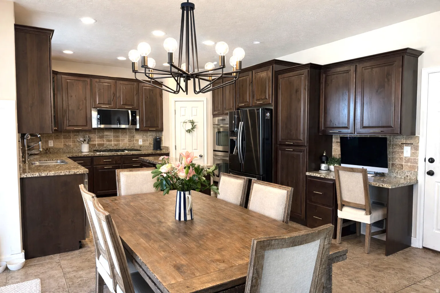 Kitchen featuring dark wood finish cabinetry, a center island, stainless steel appliances, and granite counter tops