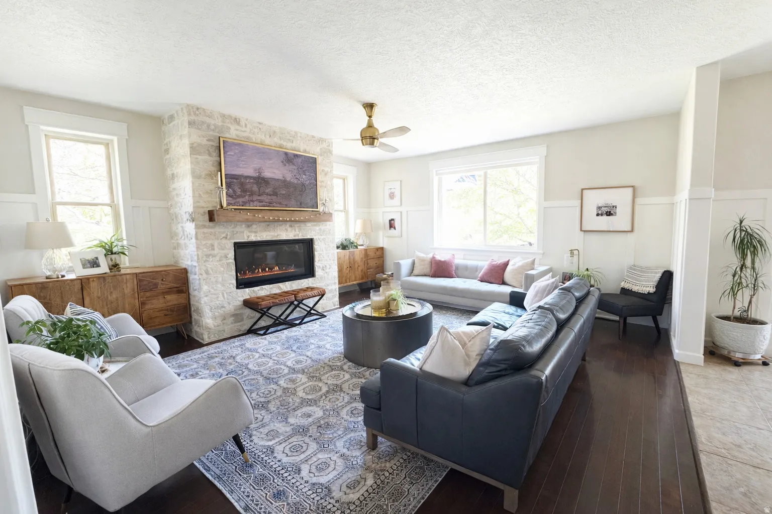 Living area featuring a wainscoted wall, a fireplace, hardwood flooring, and a textured ceiling
