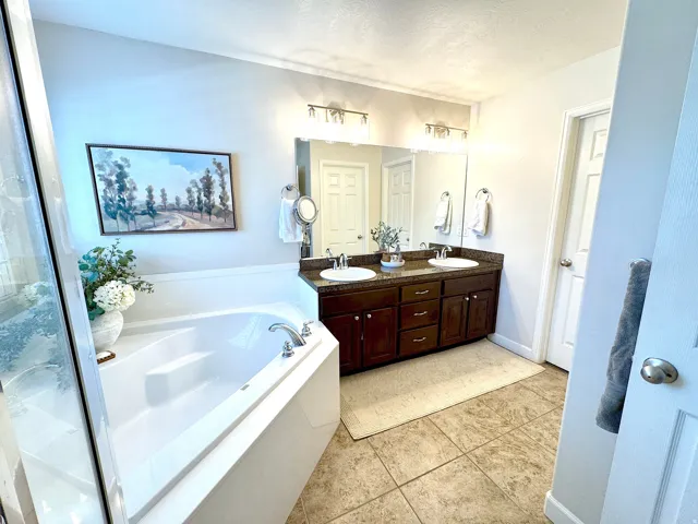 Bathroom with double vanity, a bath, light tile patterned floors, and a textured ceiling