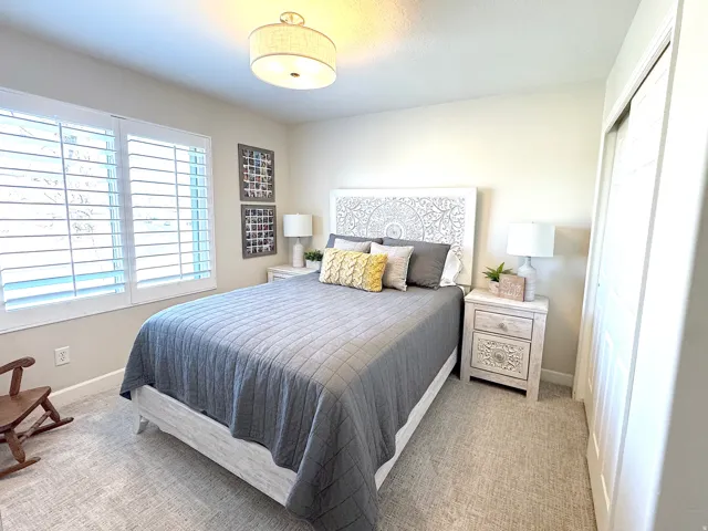 Bedroom featuring light carpet and plantation shutters