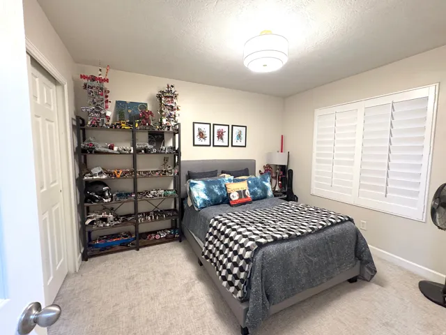 Bedroom with light carpet and plantation shutters