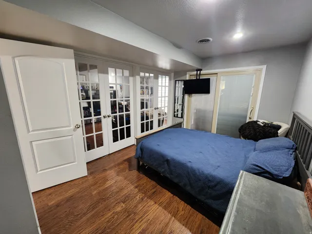 Bedroom featuring french doors and dark wood-style floors