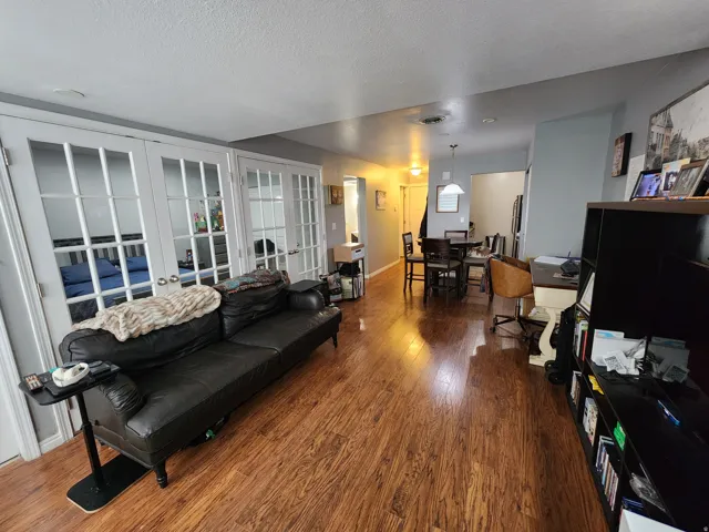 Living room featuring dark wood-type flooring, french doors, and a textured ceiling