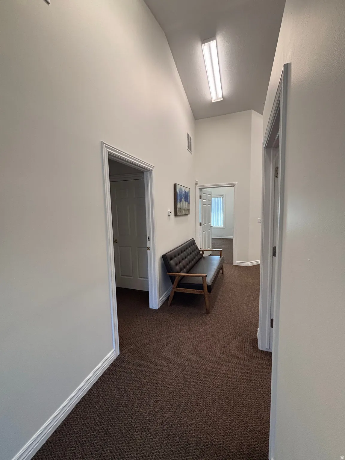 Corridor with dark carpet and a high ceiling
