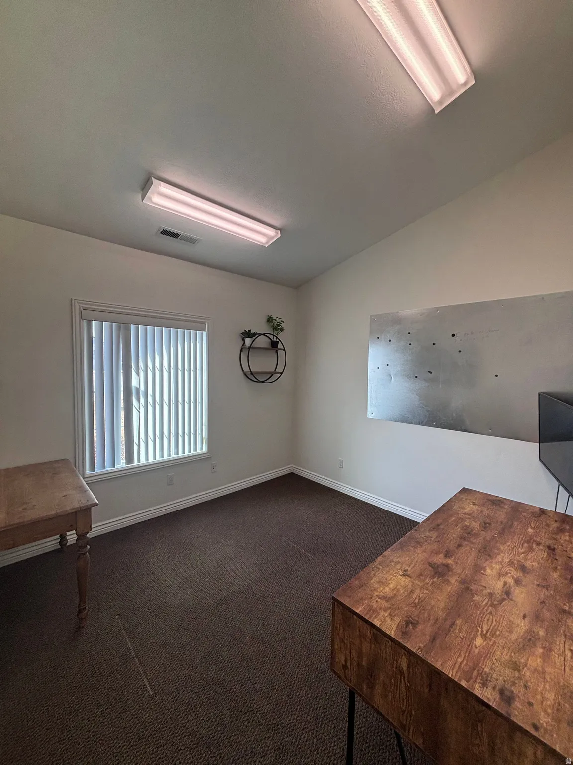 Unfurnished office with dark carpet and vaulted ceiling