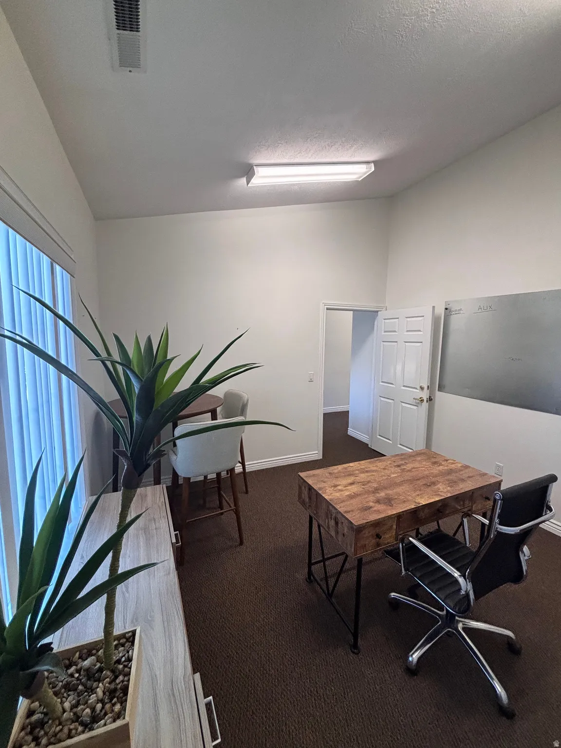 Office area featuring lofted ceiling and dark carpet