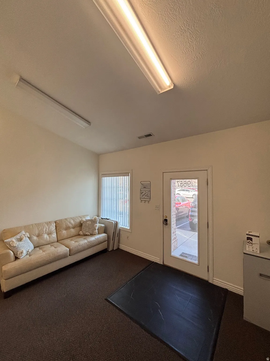 Living area featuring dark colored carpet and baseboards