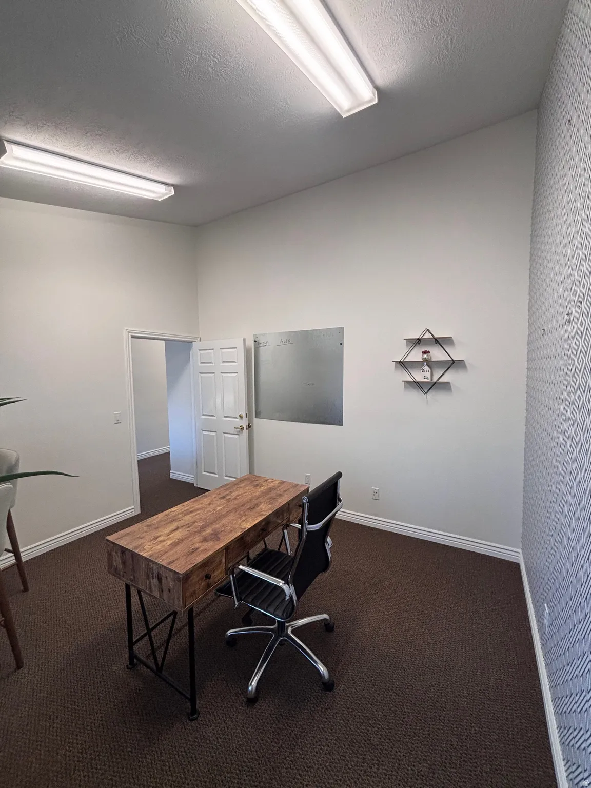 Home office featuring dark colored carpet and a textured ceiling