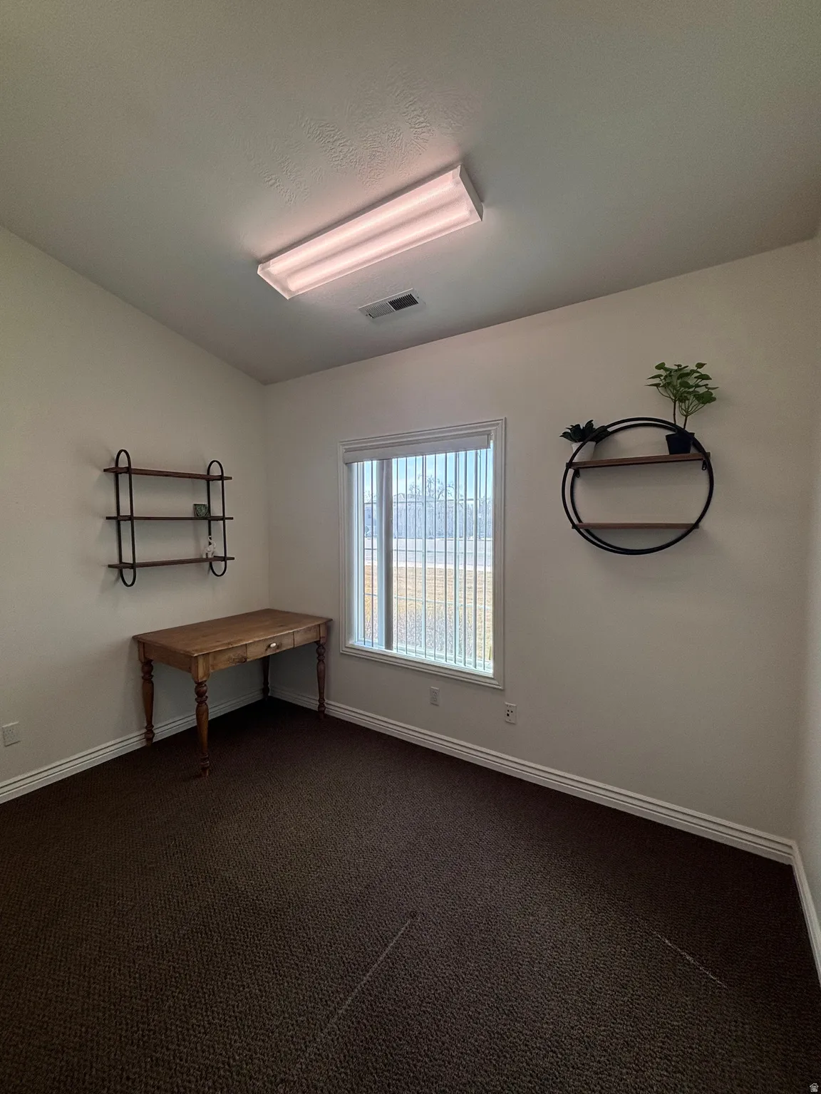 Empty room featuring dark colored carpet and baseboards