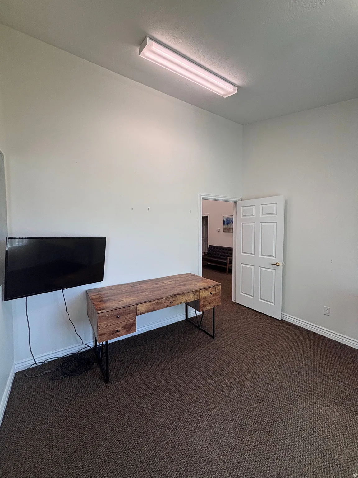 Misc room with dark carpet and baseboards