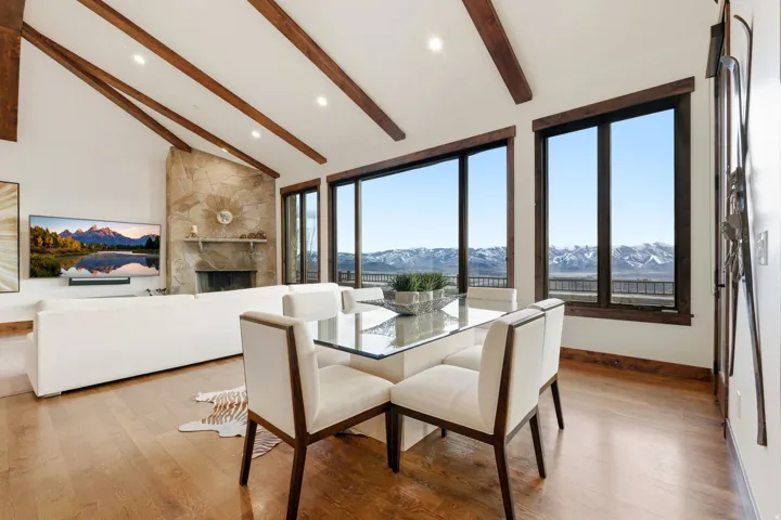 Dining space with a mountain view, light wood-type flooring, a stone fireplace, and vaulted ceiling