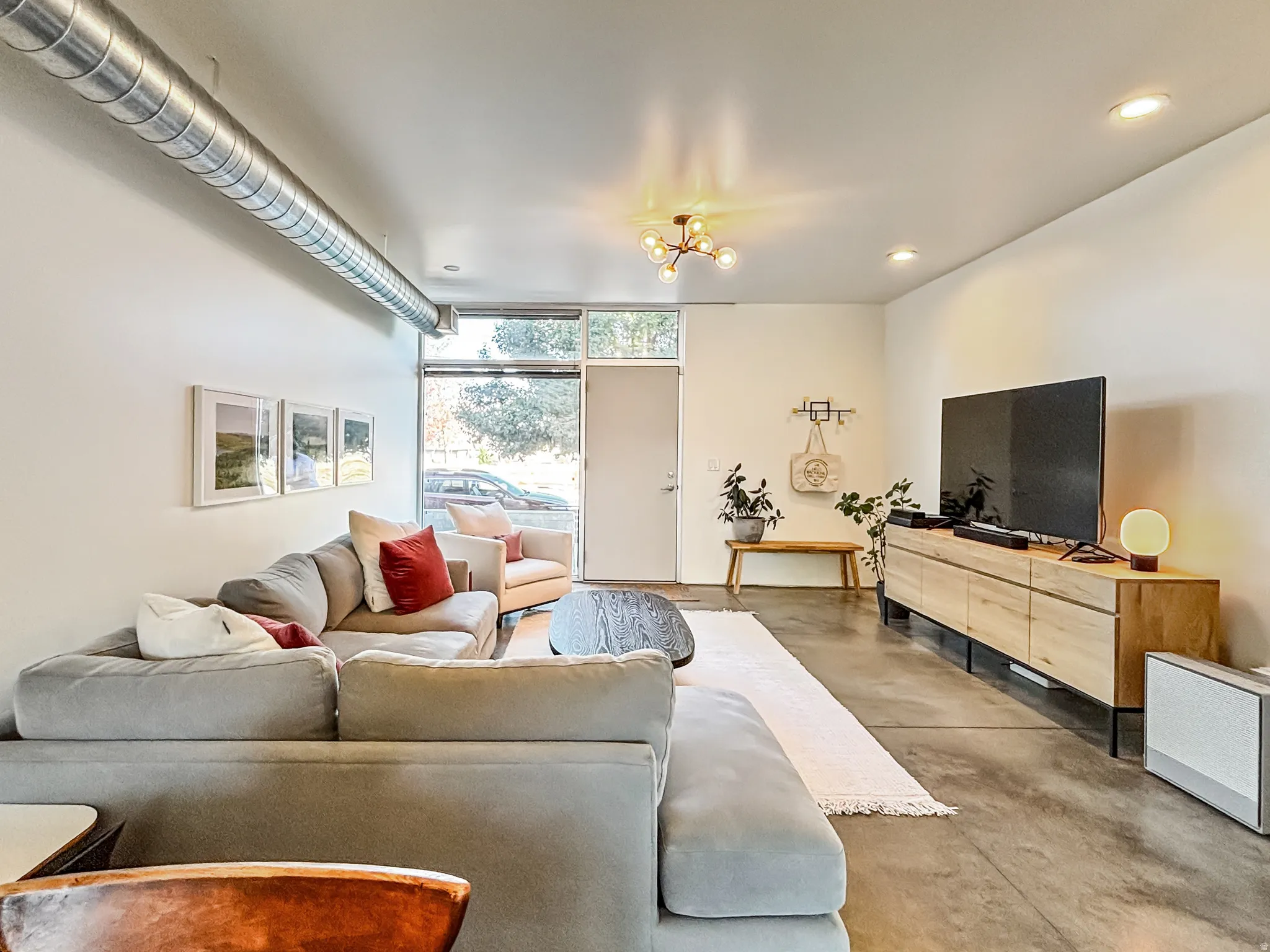Living area featuring finished concrete floors, floor to ceiling windows, and recessed lighting