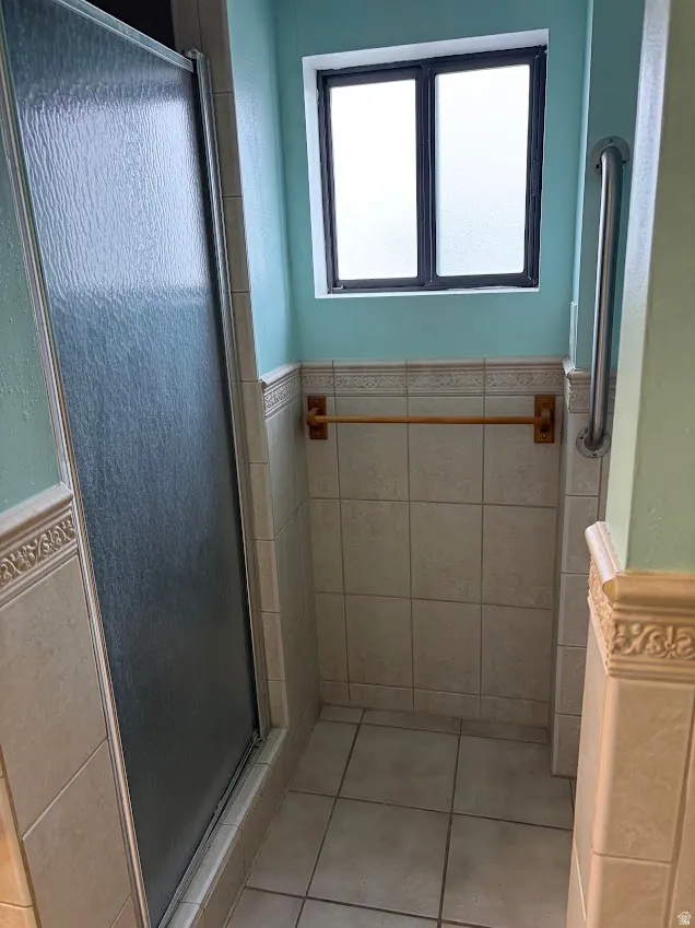 Full bathroom featuring a shower stall and light tile patterned flooring