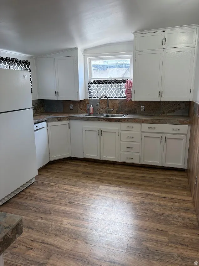 Kitchen featuring freestanding refrigerator, white cabinetry, dark countertops, and dark wood finished floors