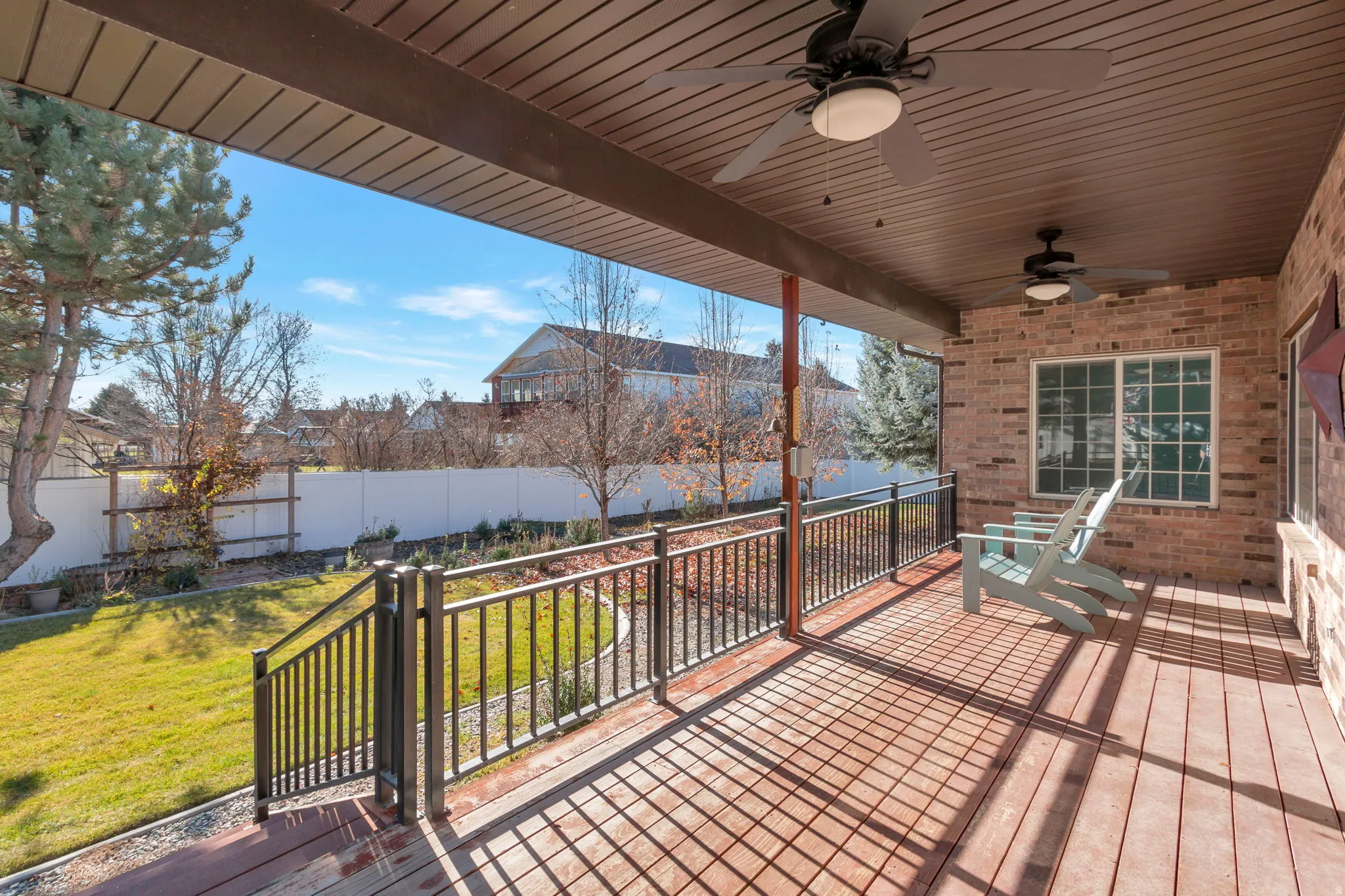 Wooden terrace featuring ceiling fan, a fenced backyard, and a residential view