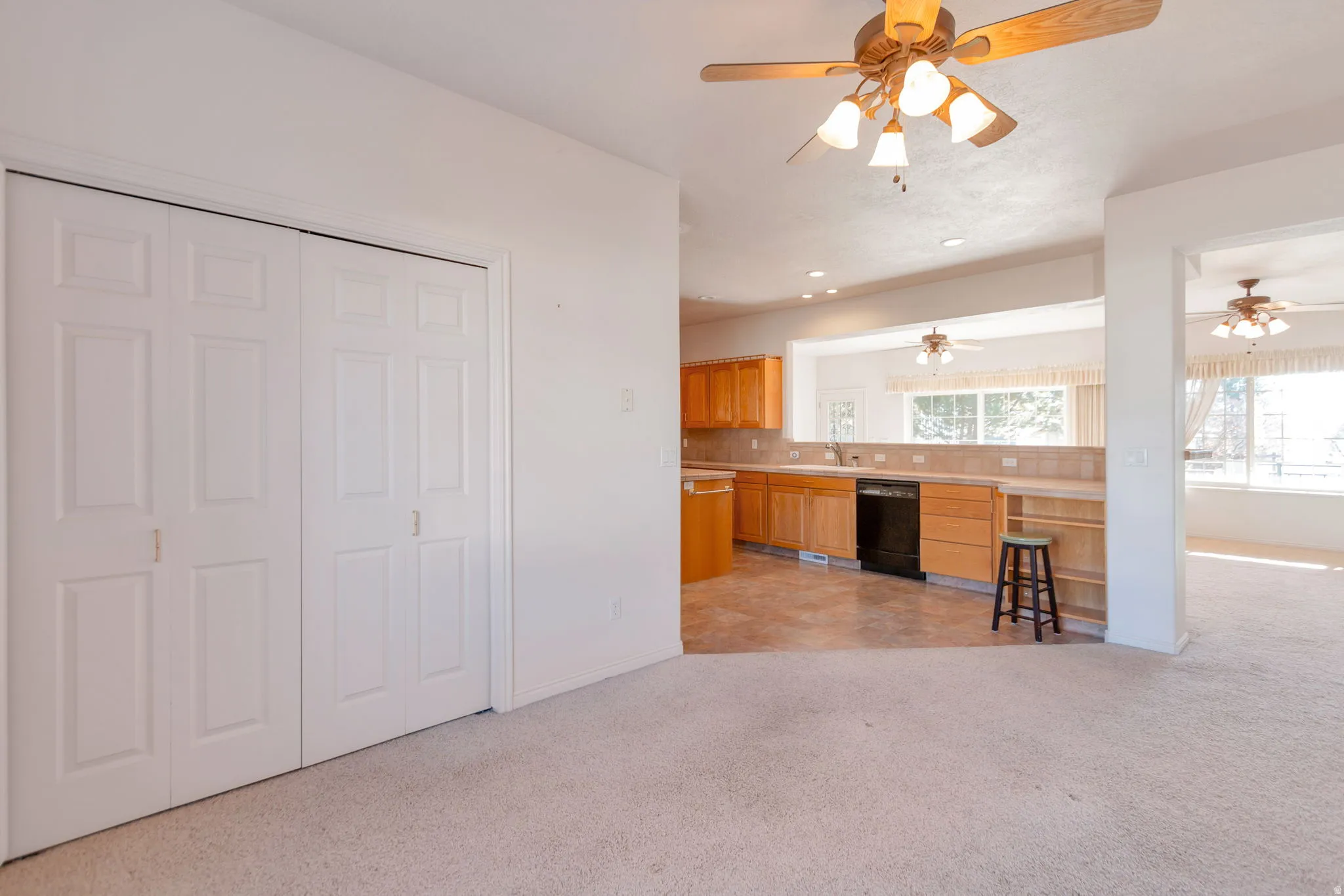 Kitchen with light countertops, dishwasher, light carpet, recessed lighting, and decorative backsplash