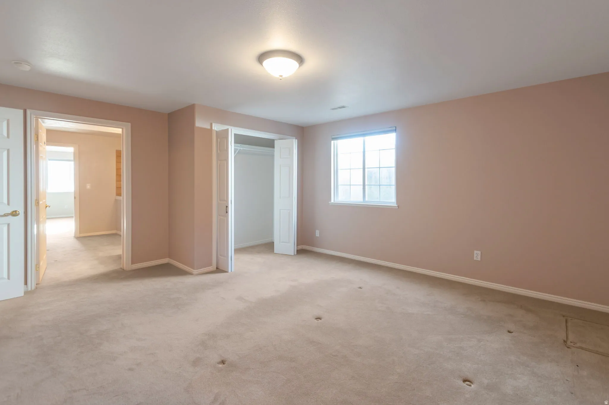 Unfurnished bedroom featuring light carpet and a closet