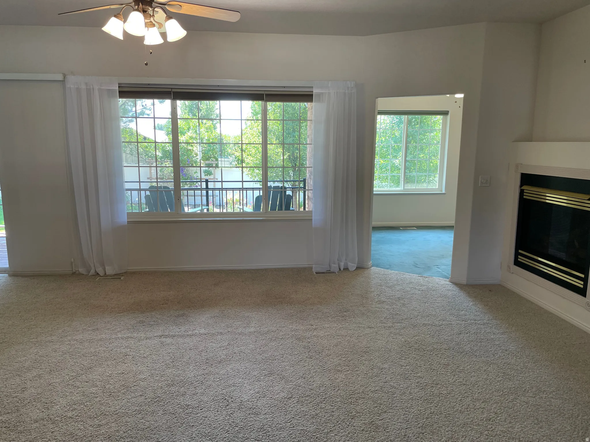 Living area featuring light-colored carpeting and a ceiling fan with light fixture