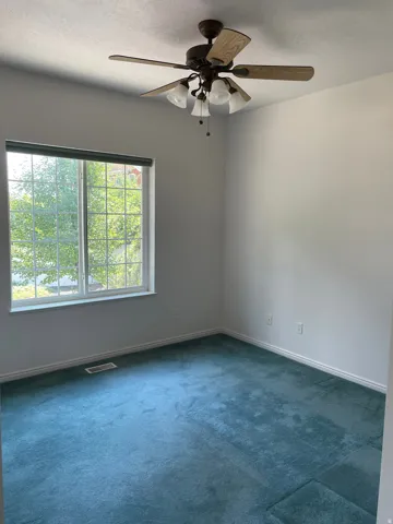 Bright room featuring teal carpeting and white baseboards