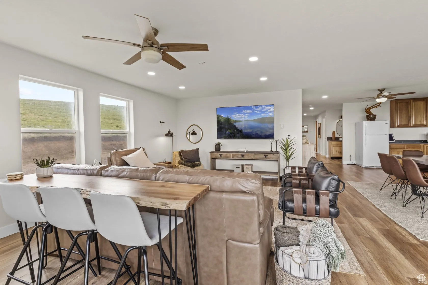 Living area with a ceiling fan, light wood-style flooring, and recessed lighting