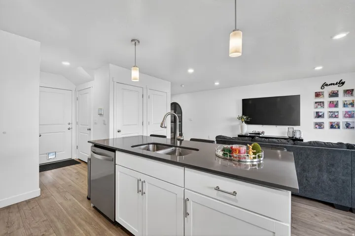Kitchen with pendant lighting, white cabinets, open floor plan, and light wood-style floors