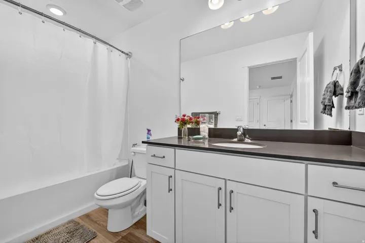 Full bath featuring vanity, shower / bath combo, and light wood-type flooring
