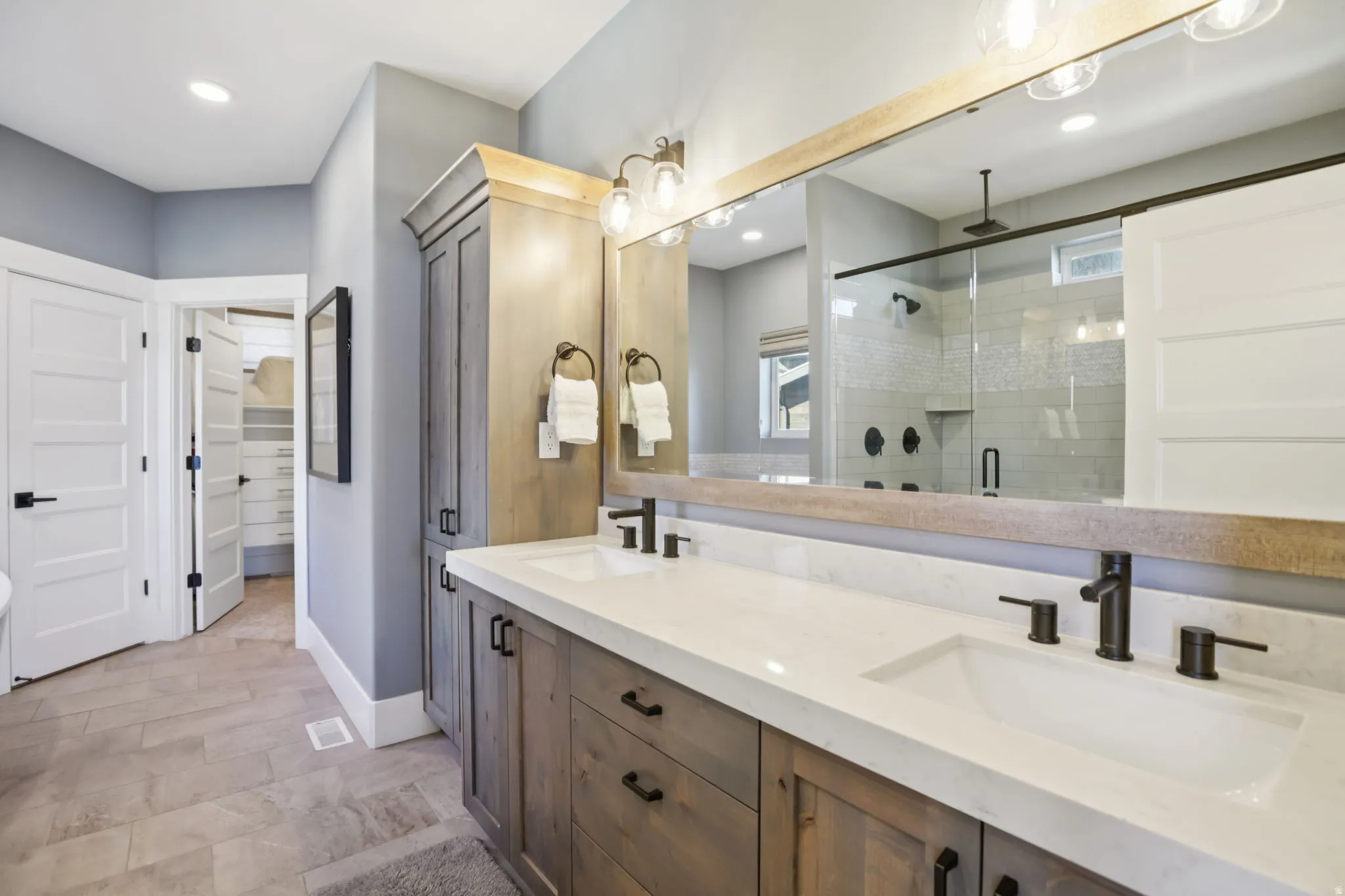Bathroom with double vanity, a stall shower, a spacious closet, and recessed lighting