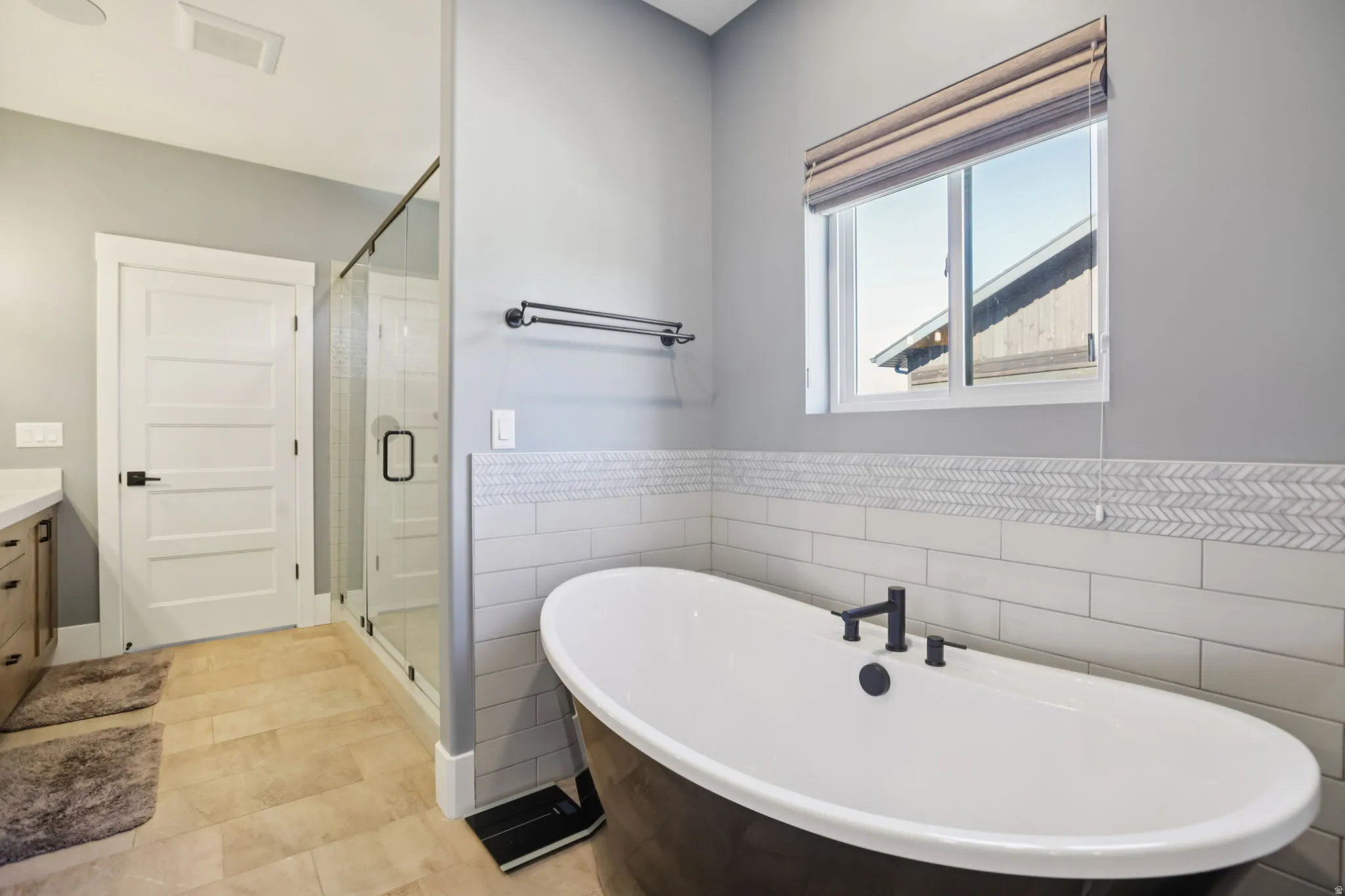 Full bathroom with a shower stall, a freestanding tub, vanity, tile walls, and light tile patterned flooring