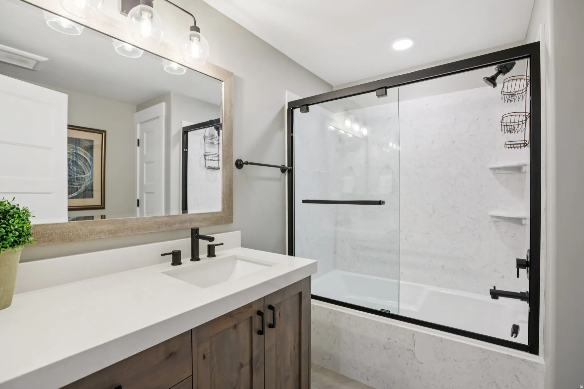 Bathroom featuring vanity and shower / bath combination with glass door