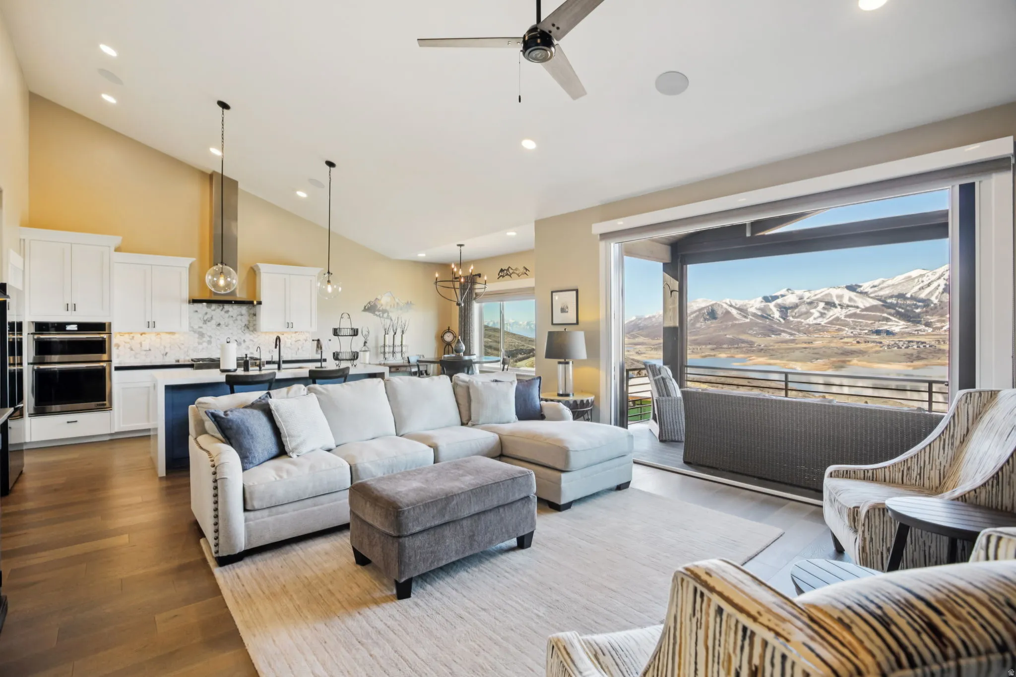 Living room with a mountain view, lofted ceiling, ceiling fan, dark wood-type flooring, and a chandelier