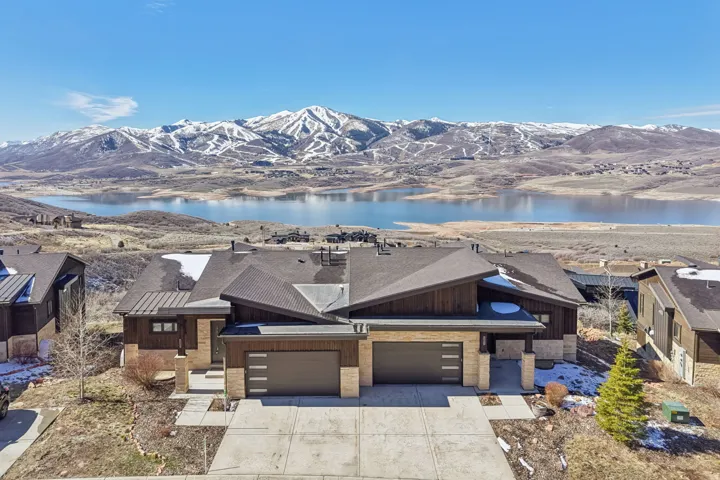 View of front facade with driveway, a garage, a water and mountain view, roof with shingles, and board and batten siding
