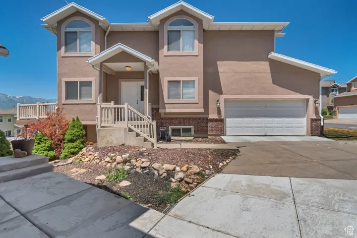View of front of home with stucco siding, concrete driveway, brick siding, and a mountain view