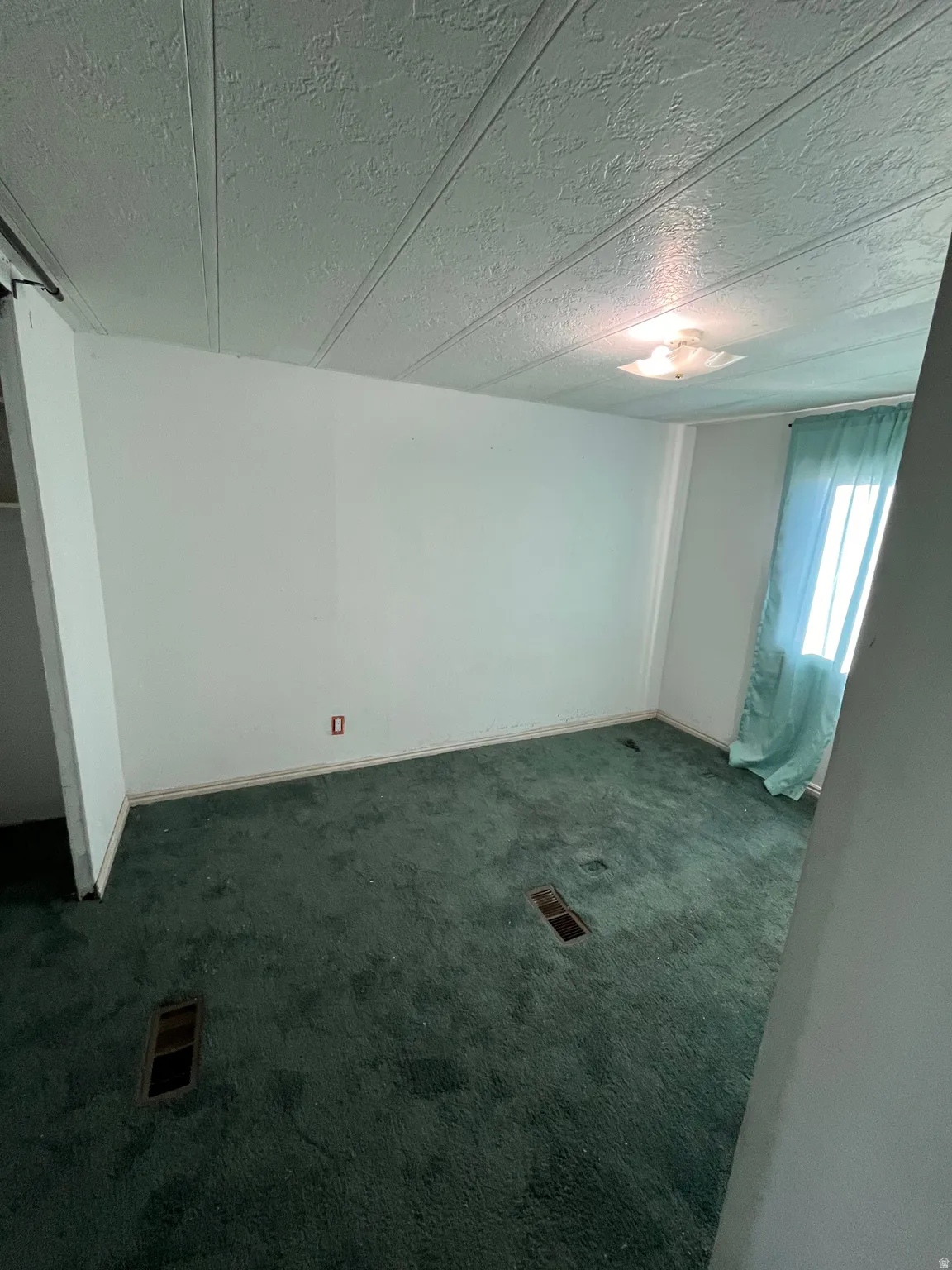 Basement with dark colored carpet and a textured ceiling
